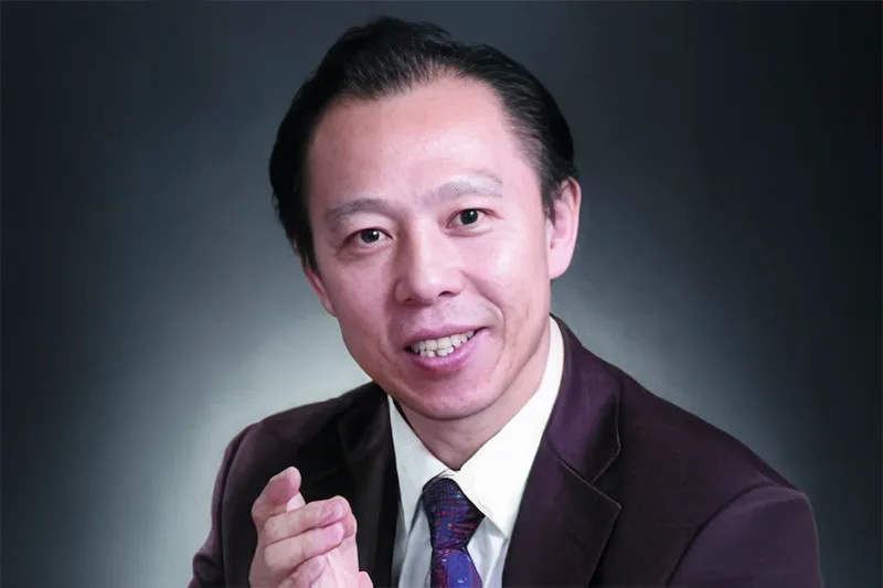 Studioportrait of Prof. Jingchun Shao, with a dark neutral background and soft lighting